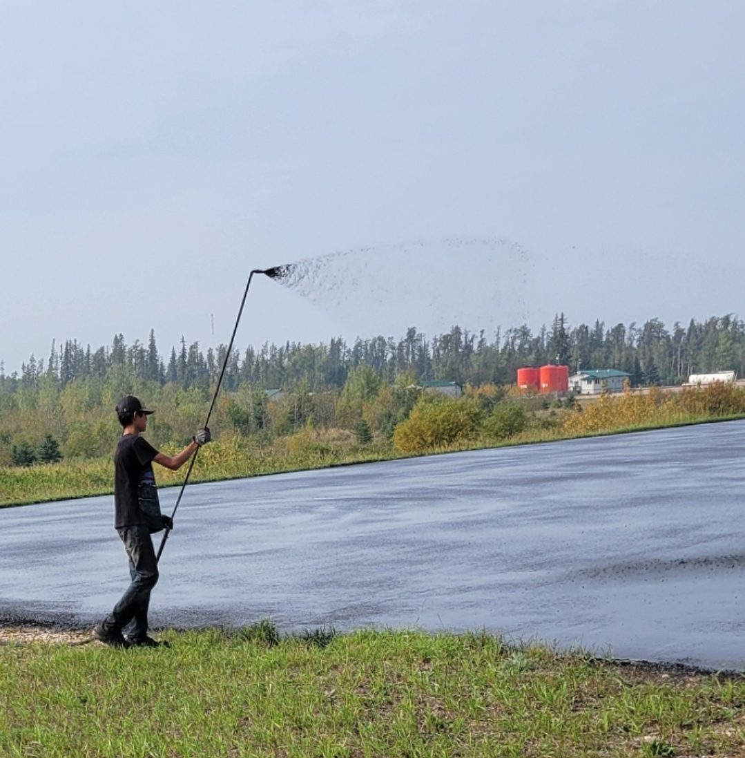 Crew spraying sealer on airport runway